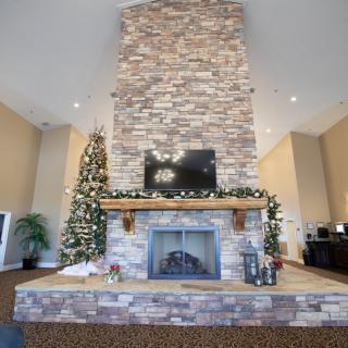 A festive living room featuring a tall stone chimney with a TV mounted above the fireplace, adorned with holiday decorations and a beautifully decorated Christmas tree.