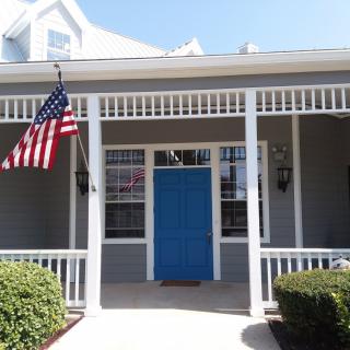 A charming house with a blue front door and an American flag on the porch.