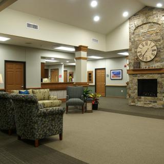 A cozy lobby interior featuring a stone fireplace and a seating area with armchairs.