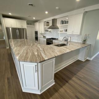 A modern kitchen featuring sleek countertops, stainless steel appliances, and wood flooring.