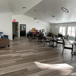 A spacious and modern lounge area with tables and chairs, featuring large windows that allow natural light to fill the room.
