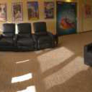 A cozy waiting area with black leather chairs and colorful posters on the walls.