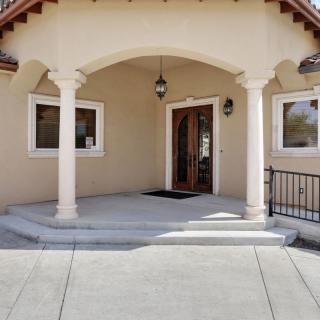 A building entrance featuring a porch with columns and a large wooden door.