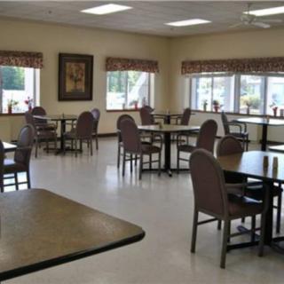 An empty dining room with tables and chairs, featuring large windows and interior decor.