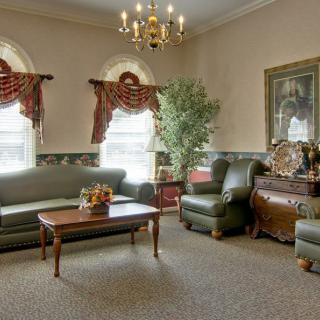 A traditionally styled living room featuring sofas, an armchair, a coffee table, and elegant curtains under a chandelier.