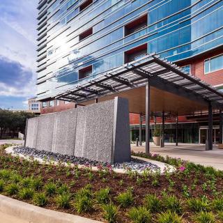 A modern building with a glass facade and landscaped exterior.