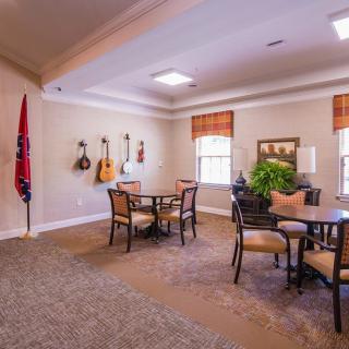 A cozy room with guitars on the wall, tables and chairs, and a decorative flag by the window.