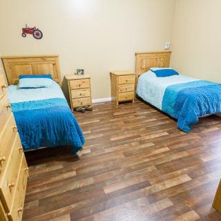 A cozy bedroom with twin beds featuring blue bedding and wooden furniture on a hardwood floor.
