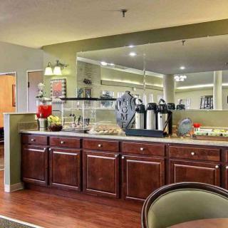 A cozy hotel breakfast area with a buffet setup including coffee and juice stations.