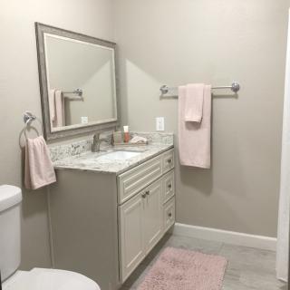 A modern bathroom with a vanity, mirror, and soft pink towels.