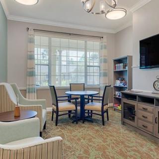 A cozy living room with comfortable seating, a round table, and a mounted television.