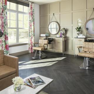A modern hair salon interior with stylish furniture, large mirrors, and ample natural light.