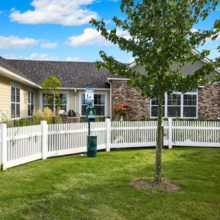 A suburban house with a fenced yard and greenery.
