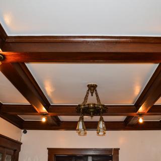 A ceiling featuring wooden beams with a central light fixture.
