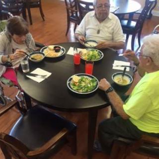 A group of seniors enjoying a meal together at a round table.