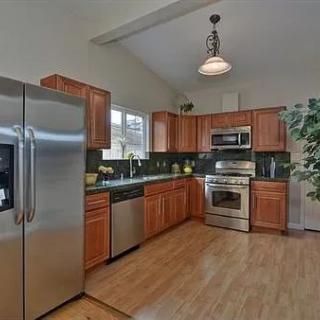 A modern kitchen featuring stainless steel appliances and wood cabinets with ample natural light.