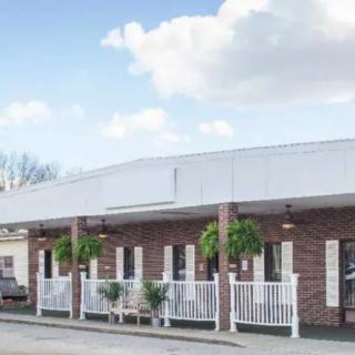 A commercial building with a brick exterior and a porch adorned with potted plants, captured during the daytime.