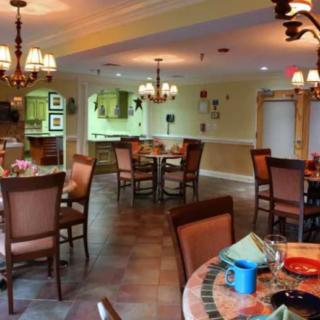 A cozy dining room with multiple tables, chairs, and chandeliers creating a warm atmosphere.