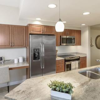 A modern kitchen featuring stainless steel appliances, wooden cabinets, and a granite countertop.