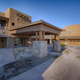 A modern building with a distinctive architectural design, featuring stone pillars and set against a desert landscape.