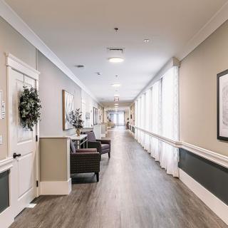 A modern hallway with seating and decor, featuring large windows and soft lighting.
