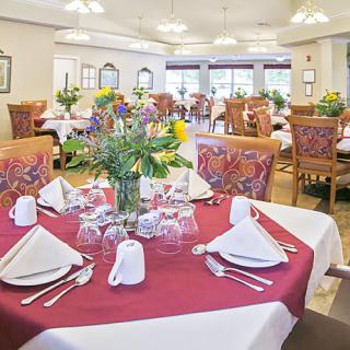 A well-decorated dining room with elegantly set tables, featuring floral centerpieces.