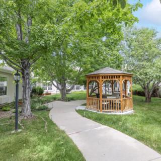A scenic view of a park with a wooden gazebo and a winding pathway surrounded by lush greenery.