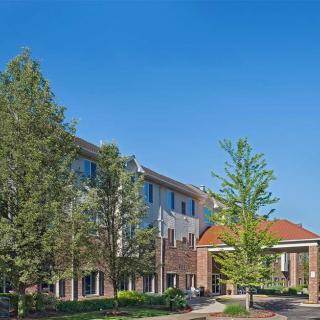 A view of a hotel building surrounded by trees under a clear blue sky.