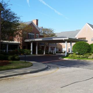 An outdoor view of a building entrance with a covered driveway and landscaped surroundings.