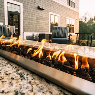 A cozy outdoor patio featuring a modern fire pit with comfortable seating.