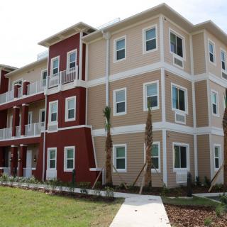 A modern apartment building with red and beige siding.