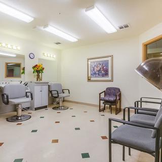 A well-lit salon interior featuring chairs, mirrors, and a waiting area.