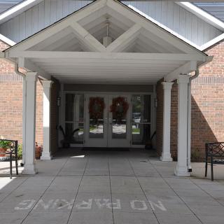 A covered entrance with columns leading to a building, displaying 'No Parking' on the pavement.