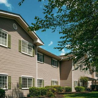 A suburban residential apartment building with trees and a clear blue sky.