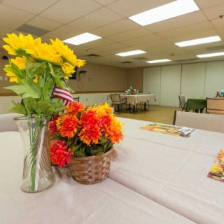 A meeting room features tables decorated with vases of sunflowers and baskets of red flowers.