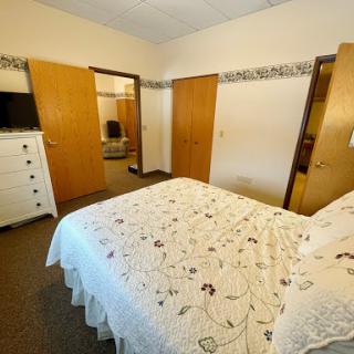 A cozy and well-furnished bedroom featuring a queen bed and wooden wardrobes.