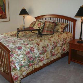A cozy bedroom with a wooden bed frame and floral-patterned bedding, accompanied by a nightstand and lamps.