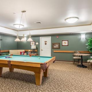 A cozy billiards room with a pool table and comfortable seating.