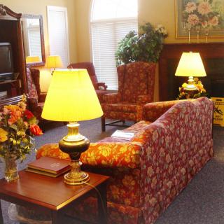 A cozy living room with traditional decor featuring sofas, lamps, and a coffee table with flowers.