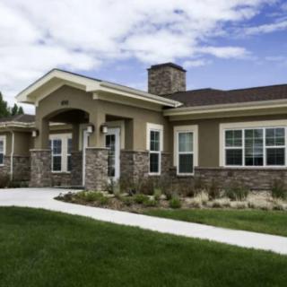 A modern residential house with a stone facade and landscaped front yard.