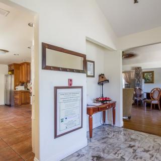 A spacious interior featuring a hallway with adjacent views of a kitchen and dining room, adorned with decorative furniture and wall art.