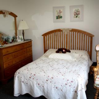 A cozy and neatly arranged bedroom featuring a wooden bed, dresser, and tasteful decor.