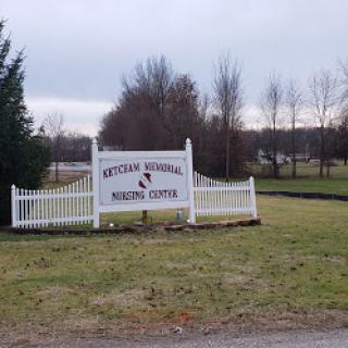 Entrance sign to a nursing center, surrounded by open fields and trees.