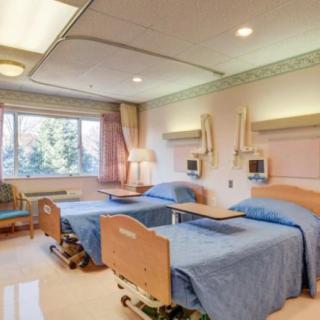 A well-lit hospital room with two patient beds and medical equipment.