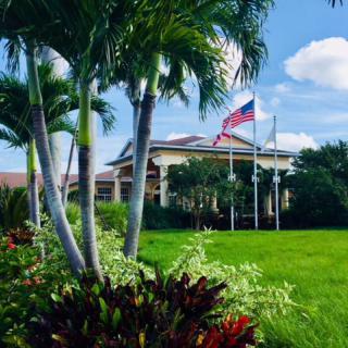 A picturesque view of a building with palm trees and an American flag on a sunny day.