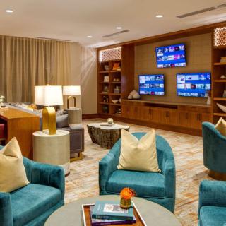 A modern living room with plush blue chairs, a large television display, and a cozy reading area.