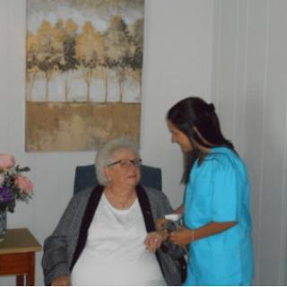 A nurse attends to an elderly woman in a healthcare setting.
