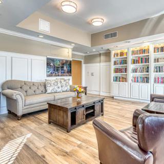 A cozy living room featuring a comfortable sofa, armchairs, coffee table, and a bookshelf filled with books.
