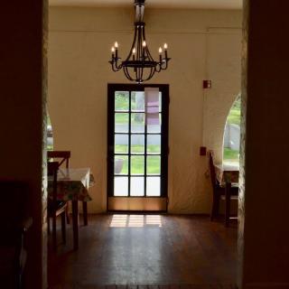A cozy dining room with a chandelier and natural light streaming through a glass door.