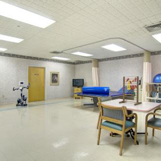 A modern rehabilitation room equipped with therapy tools and a robotic assistant.